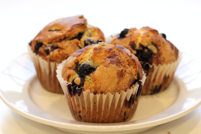 Three blueberry muffins on a white plate