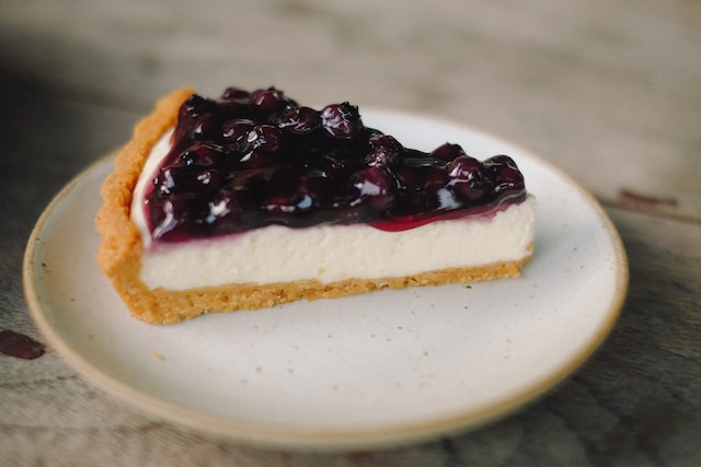 A slice of blueberry cheesecake on a ceramic plate